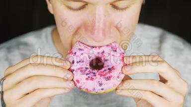 一个<strong>饥饿</strong>的年轻人吃甜甜圈的肖像